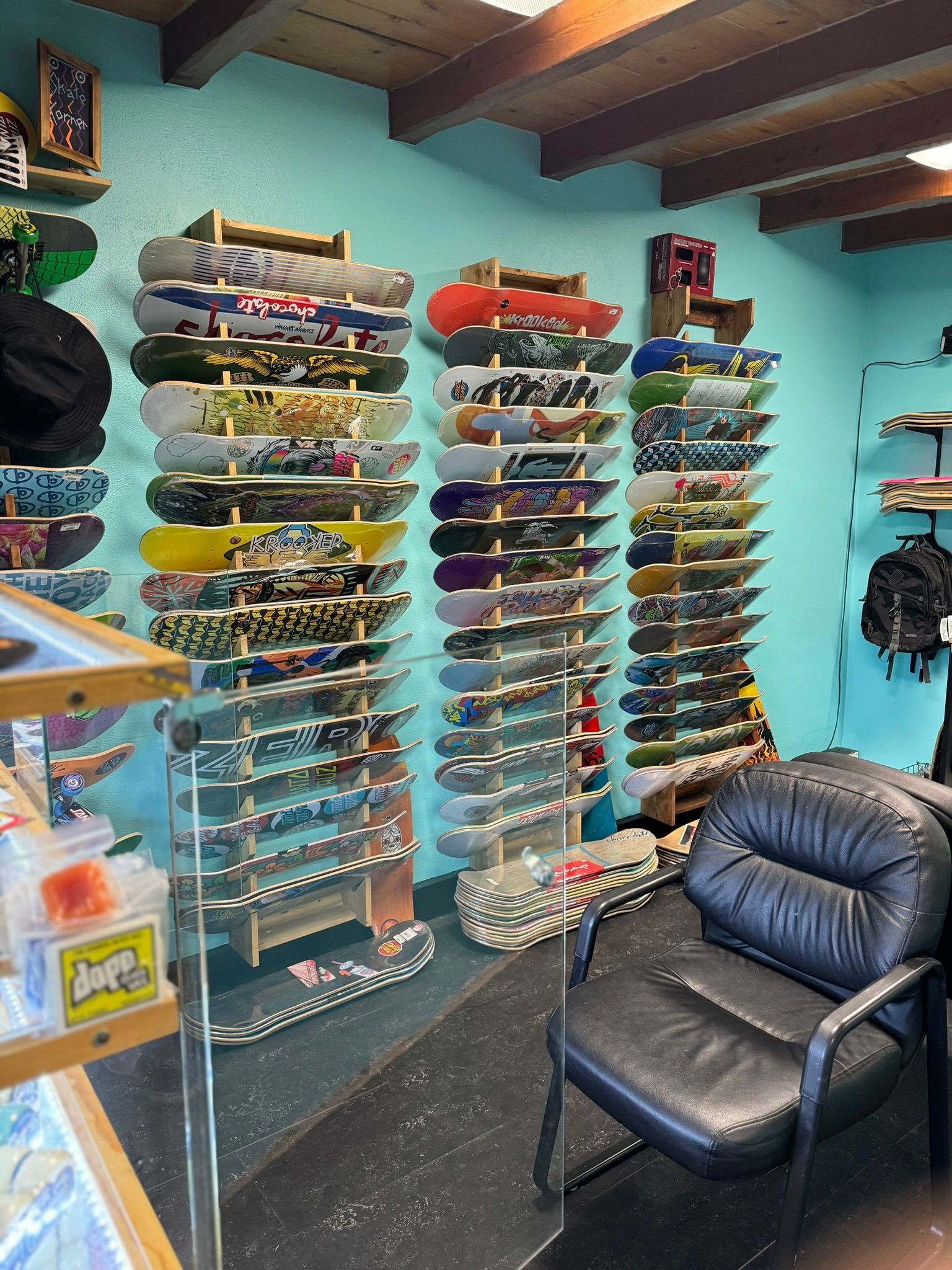 Skateboard shop wall with rows of colorful decks and a black leather chair in the foreground