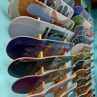Stack of colorful skateboards displayed vertically on a rack, shown from a low angle.