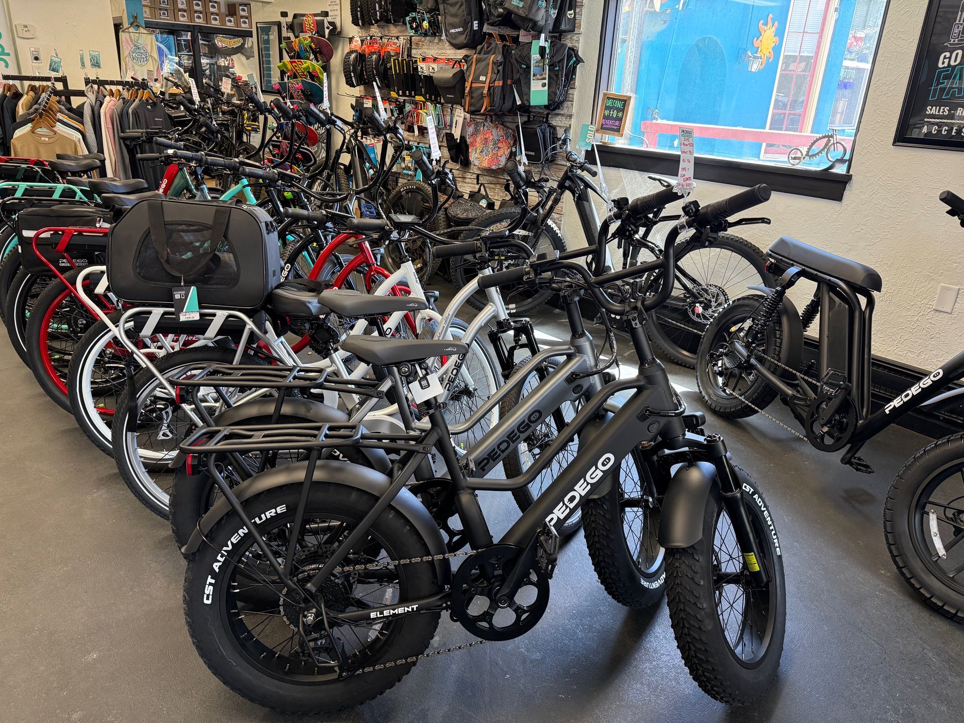 Rows of bicycles and cargo bikes displayed in a shop, with black and red frames in the foreground.