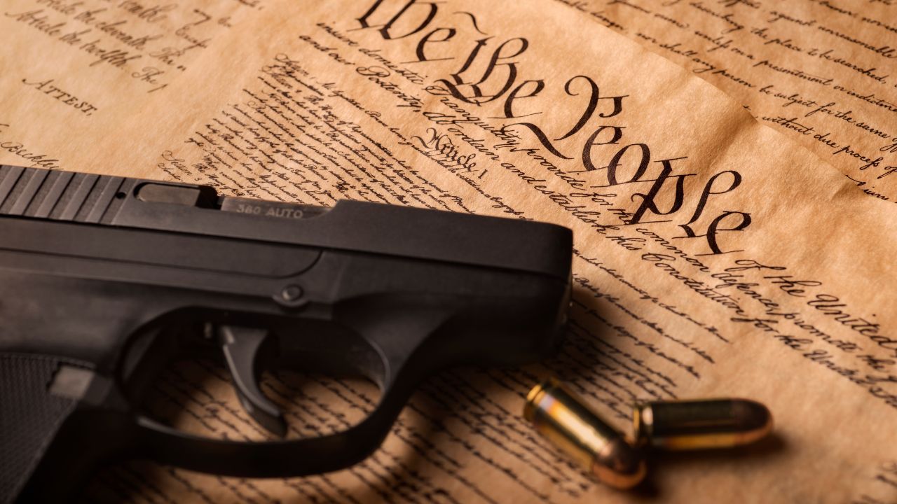 Black handgun and two bullets on a U.S. Constitution document background