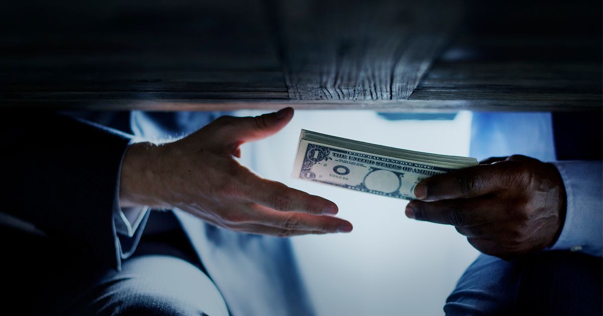 Hands exchanging money under a table, suggesting a bribe.