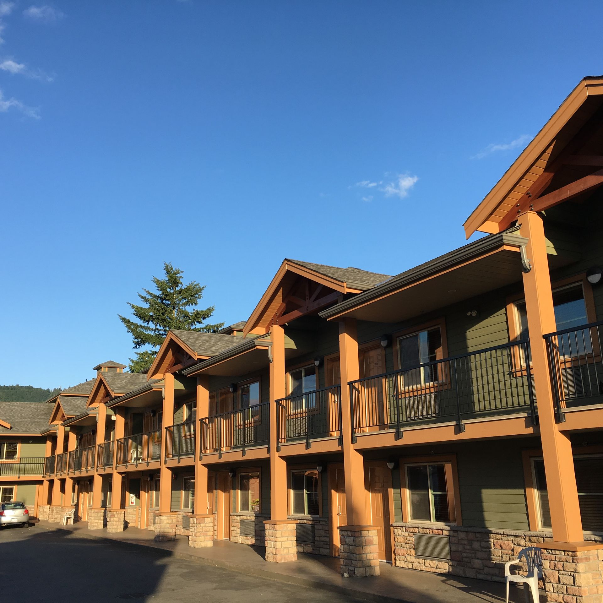 A two-story hotel with green siding, brown trim, and balconies under a blue sky.