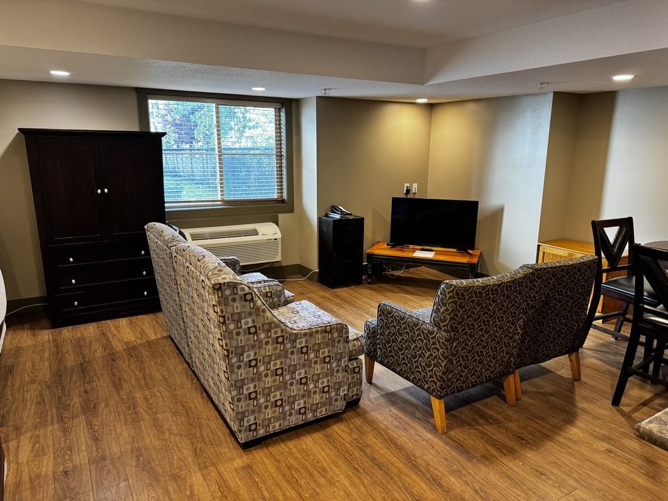 Living room with sofa, coffee table, TV, wooden floor, and a patterned rug.