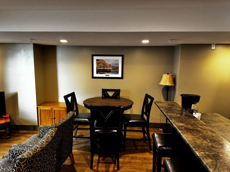 Dining area with a round table, four chairs, a sofa, and a countertop with stools.