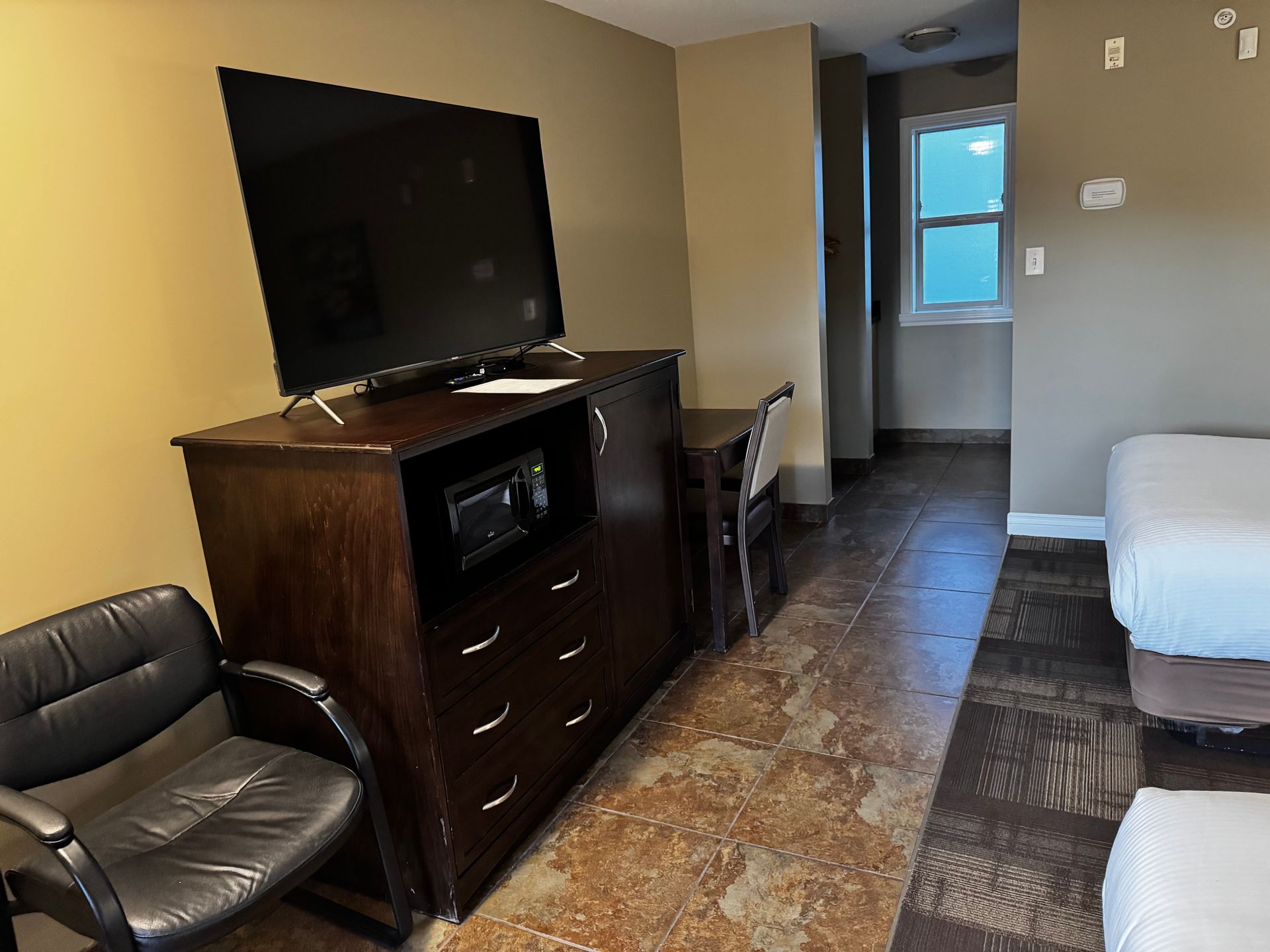 Hotel room: TV on dresser, chair, desk, beds. Interior with window.
