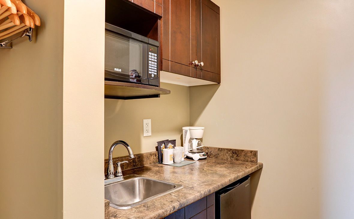 Small kitchenette with microwave, sink, countertop, and mini-fridge.