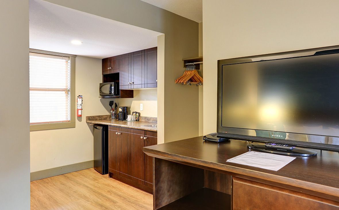 Hotel room with a kitchenette and desk. Includes a TV, microwave, and small refrigerator.
