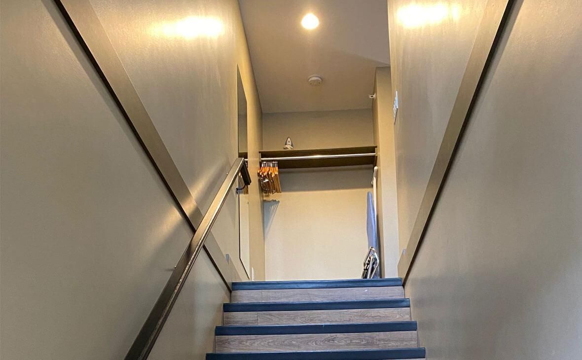 Staircase with blue and gray carpet leads up to a hallway with a light fixture and open doorway.