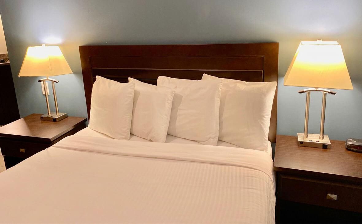 Bedroom with white bed, pillows, and lamps on bedside tables.
