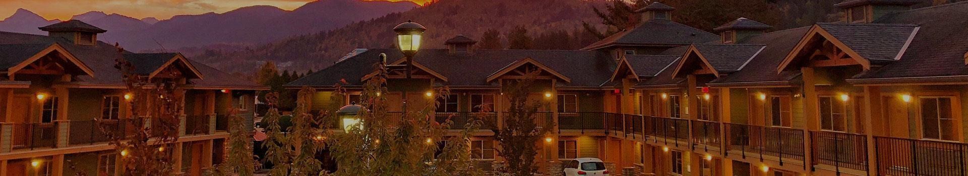 Hotel at dusk with exterior lights on; mountains in the background.