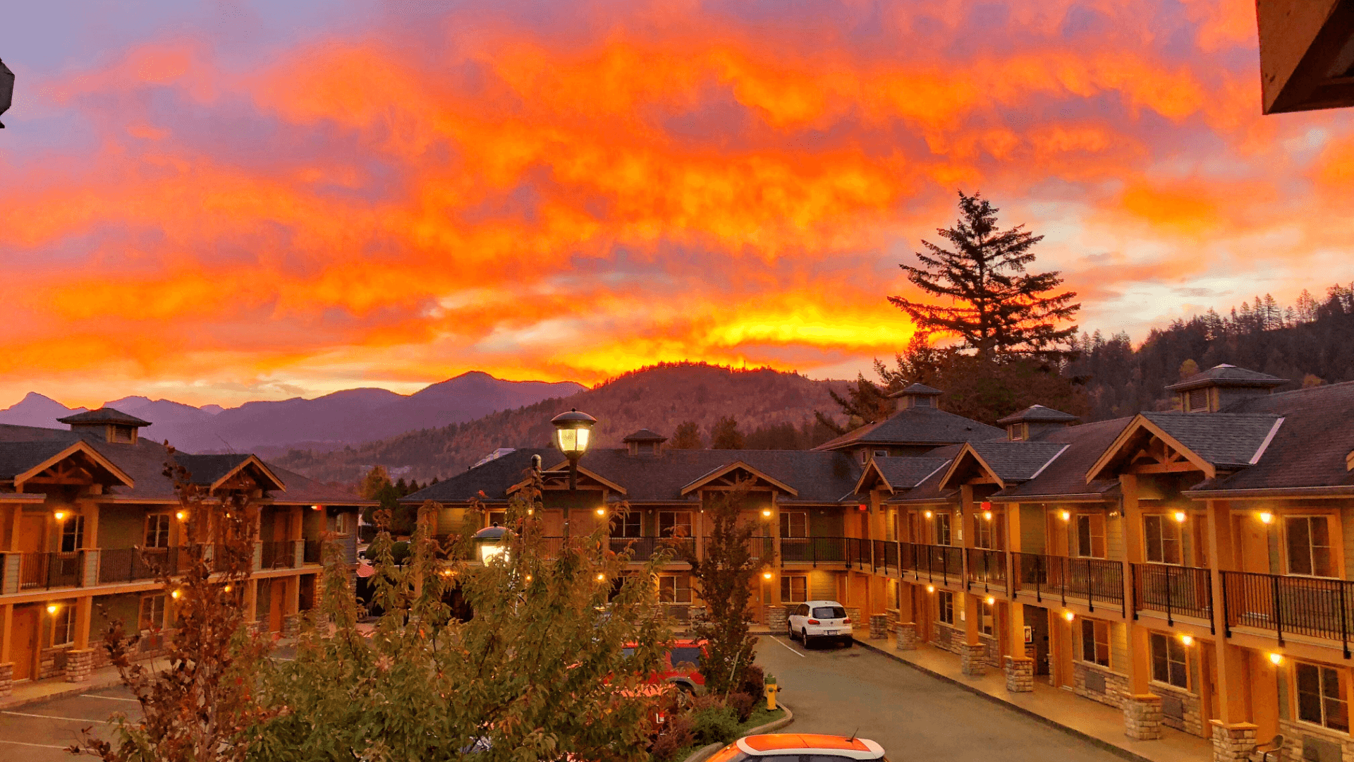 Sunset over a lodge, orange and purple sky, mountains in the background.