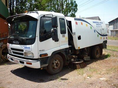 White Isuzu street sweeper truck parked outdoors — Industrial Power Sweeping Services Pty Ltd In Knuckey Lagoon, NT