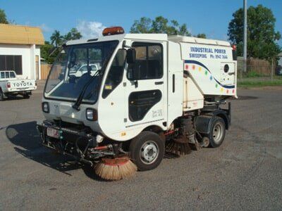 White street sweeper truck with side brushes, parked on pavement — Industrial Power Sweeping Services Pty Ltd In Knuckey Lagoon, NT