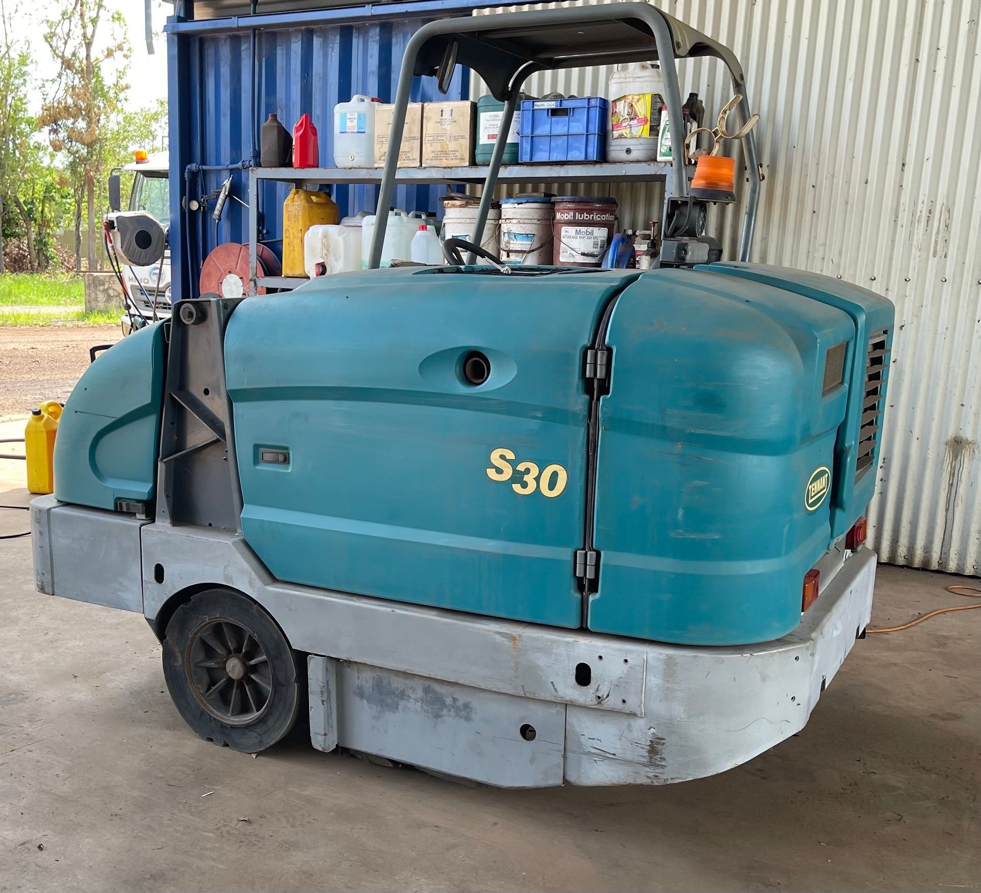 Teal street sweeper parked on pavement beside a grassy area and trees — Industrial Power Sweeping Services Pty Ltd In Knuckey Lagoon, NT