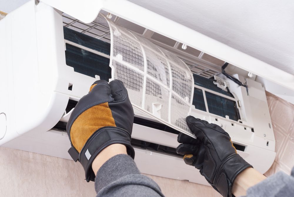 A Person Is Cleaning The Filter Of An Air Conditioner — Law Air Conditioning In Annandale, QLD