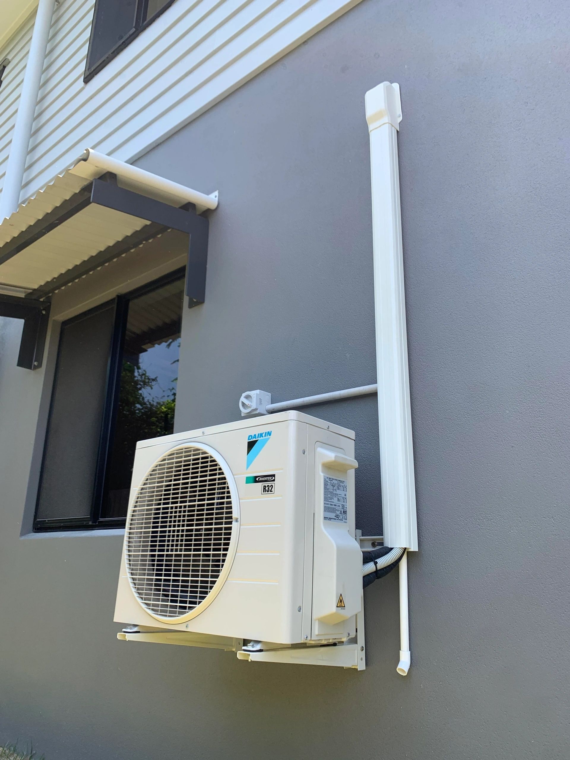 A White Air Conditioner Is Mounted On The Side Of A Building — Law Air Conditioning In Annandale, QLD