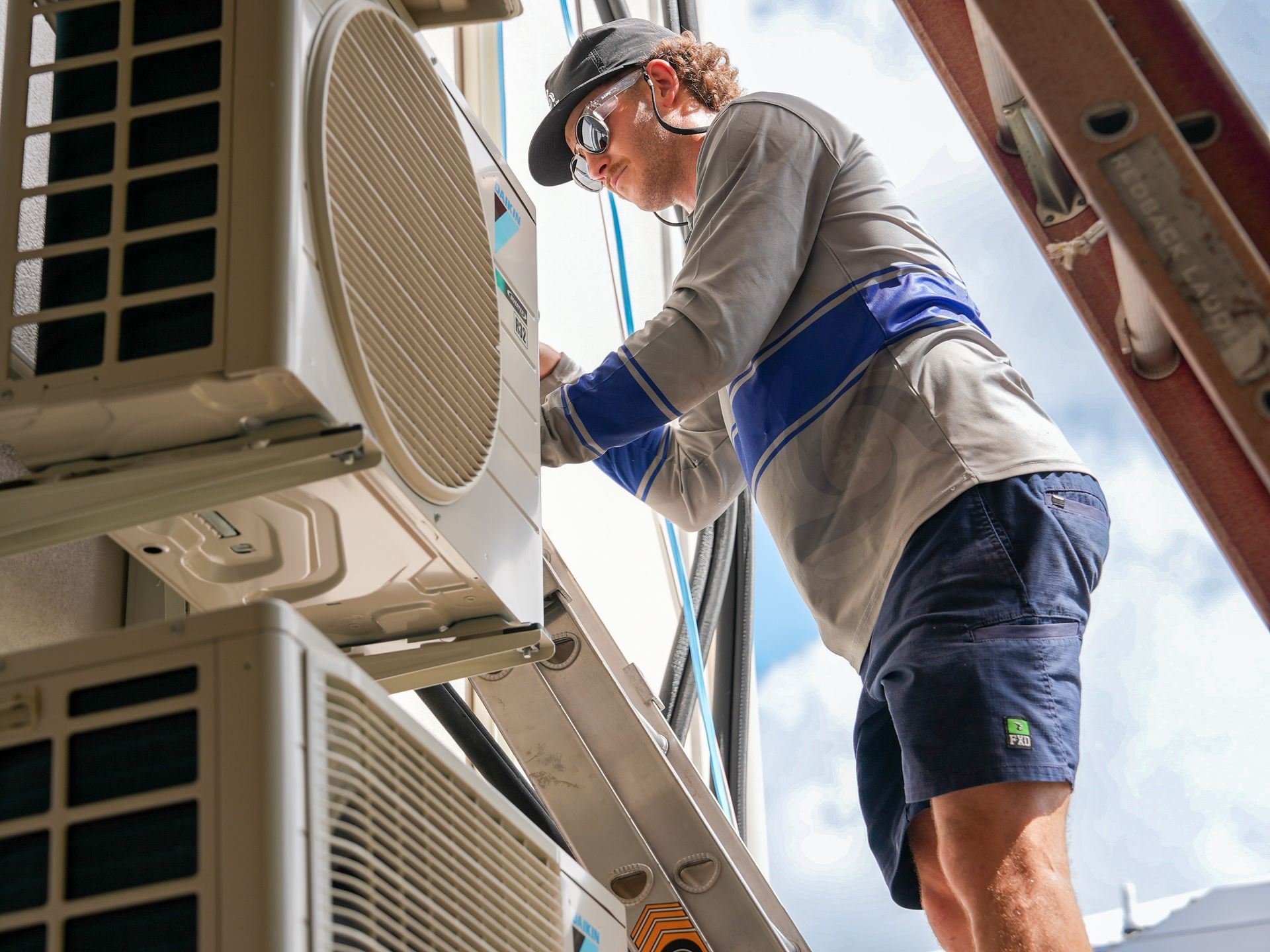 Two People Are Working On A Large Fan On A Table — Law Air Conditioning In Annandale, QLD