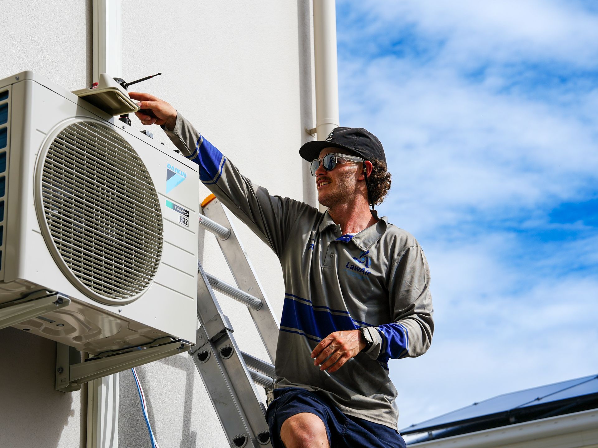 A Man Is Cleaning The Filter Of An Air Conditioner  — Law Air Conditioning In Annandale, QLD