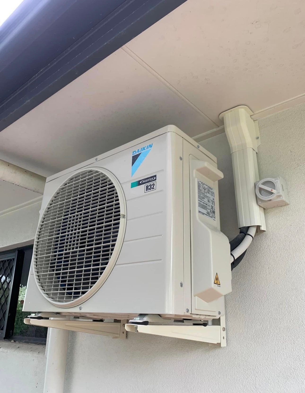 A White Air Conditioner Is Mounted On The Side Of A Building — Law Air Conditioning In Annandale, QLD