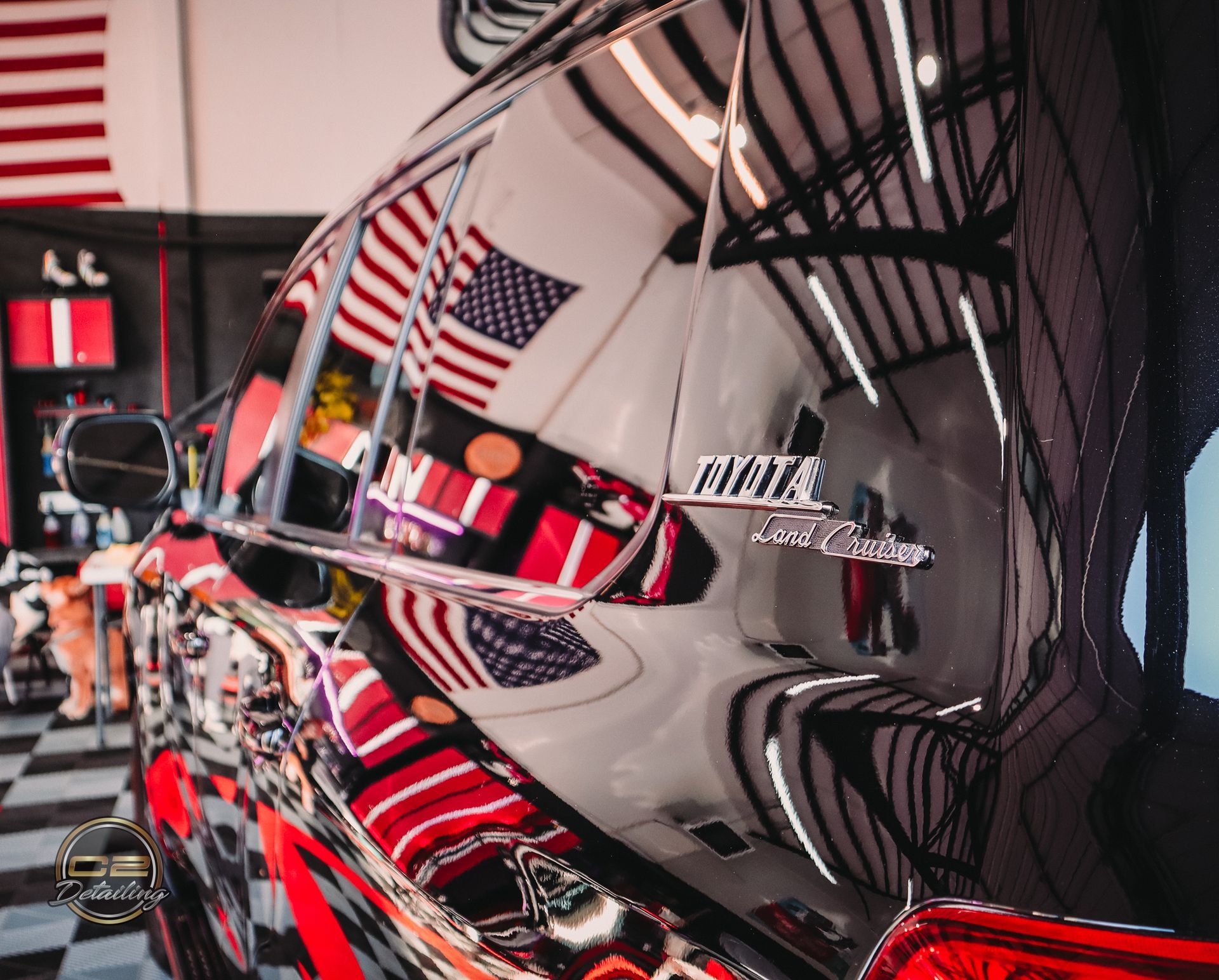 A black car is parked in a garage with american flags on the walls.