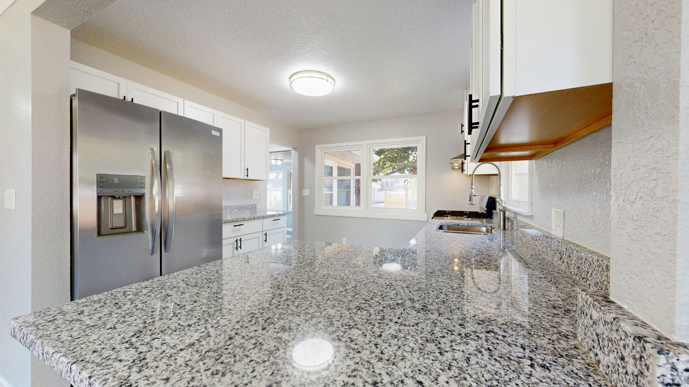 White kitchen cabinets with marble countertops and backsplash, under construction.