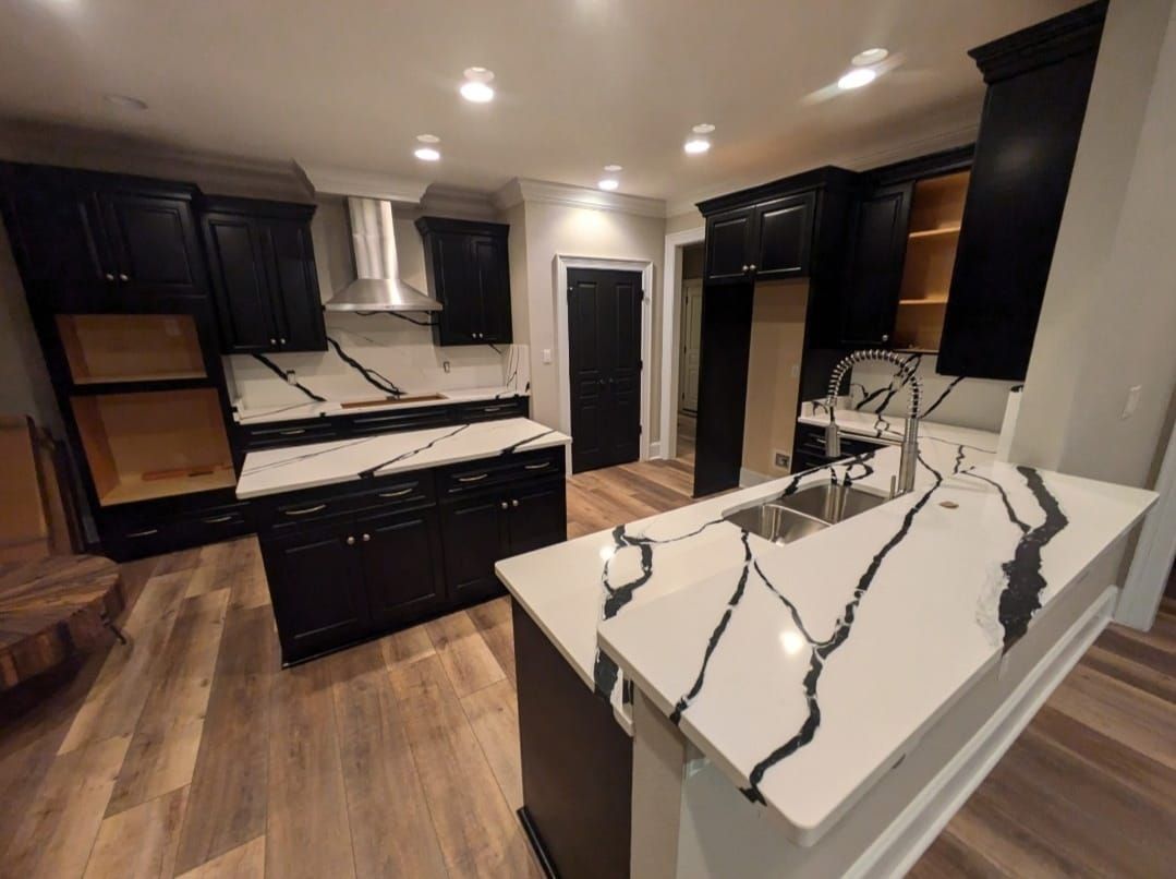 Modern kitchen with dark cabinets, white marble island, and hardwood floors