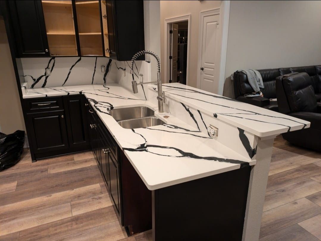 Modern kitchen with a damaged white marble island and countertop, appearing cracked and broken, with dark cabinetry.