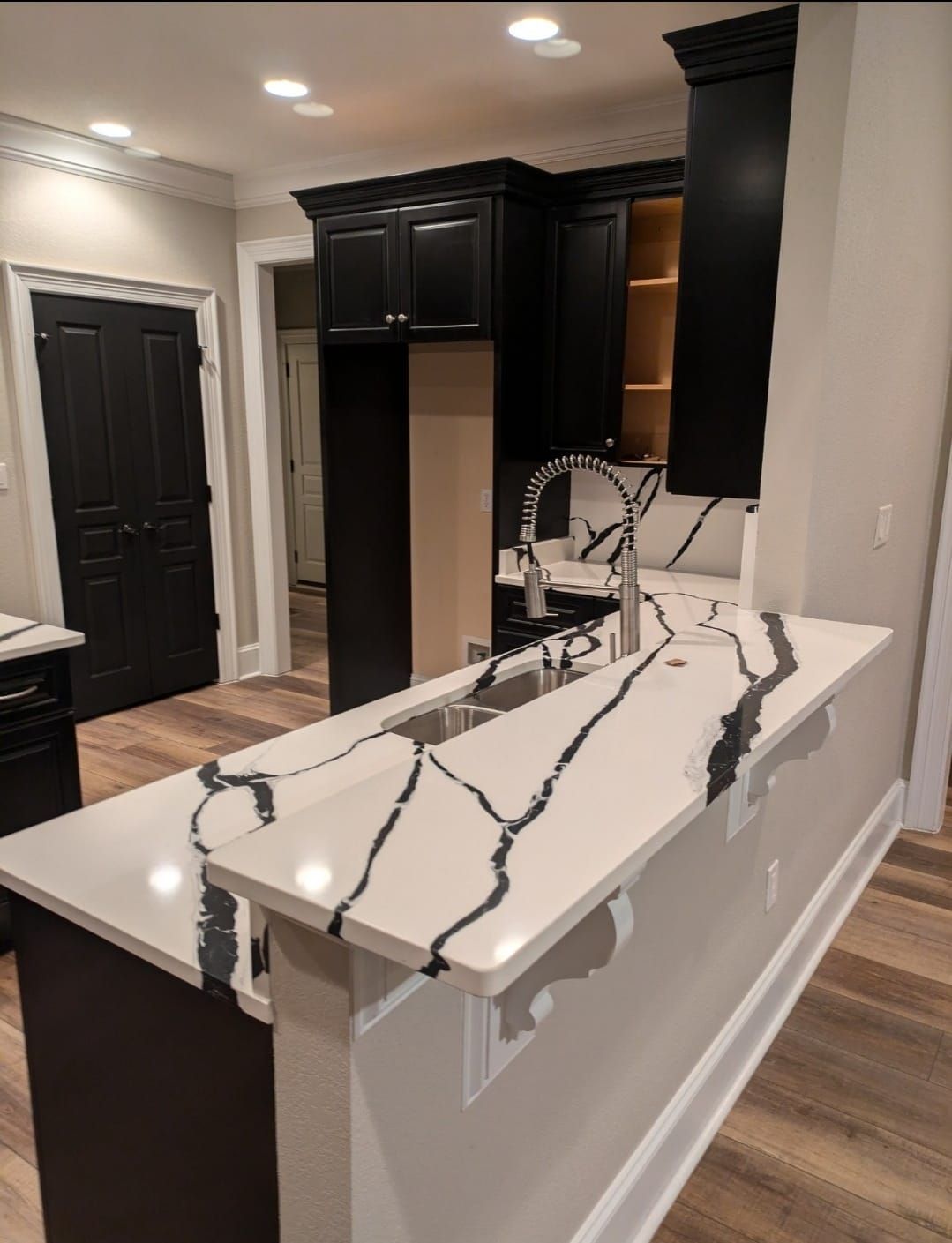 Modern kitchen with black cabinets and white island countertop with gray veining