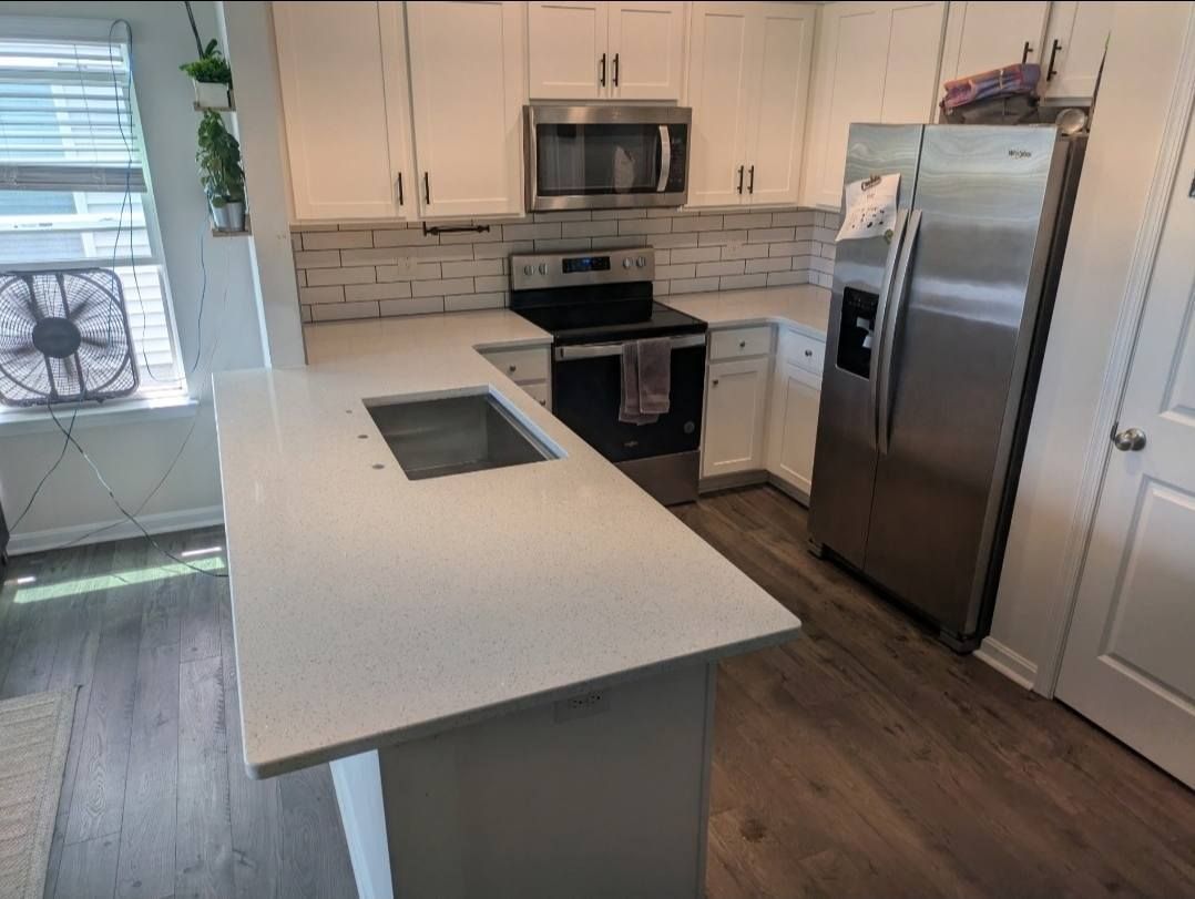 Modern kitchen with white cabinets, stainless appliances, island, and hardwood floors