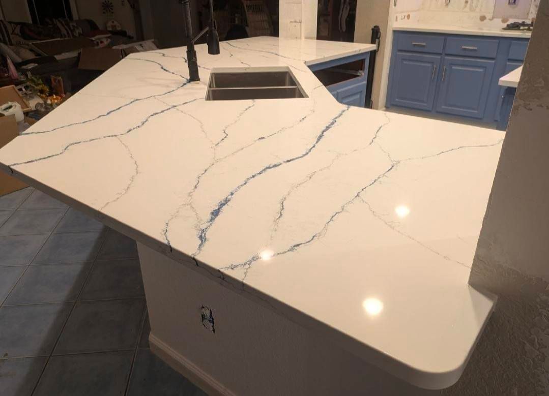 White quartz kitchen island with gray veining and a built-in cooktop, shown in a kitchen interior