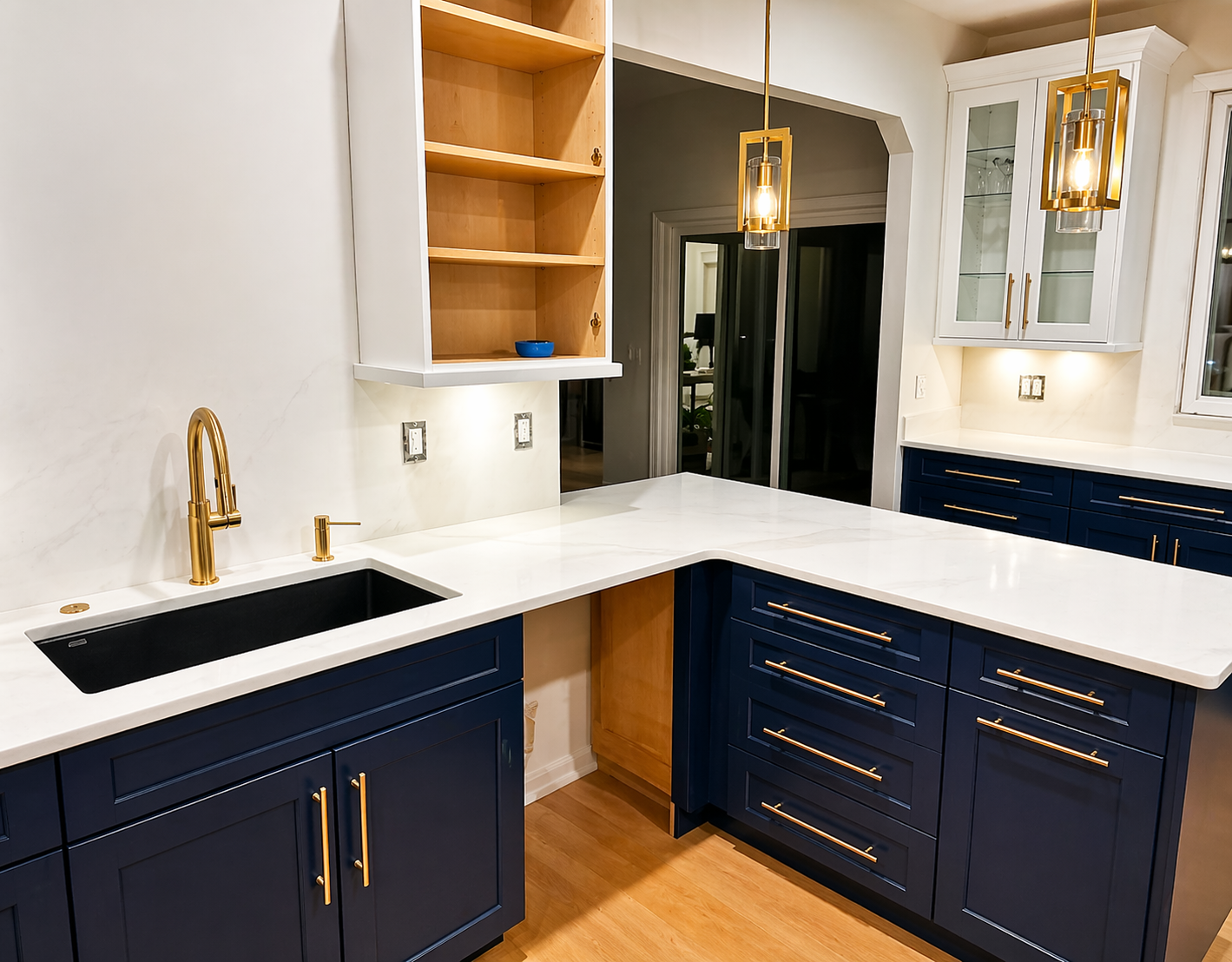 Modern kitchen with navy cabinets, white countertops, gold fixtures, and built-in shelving