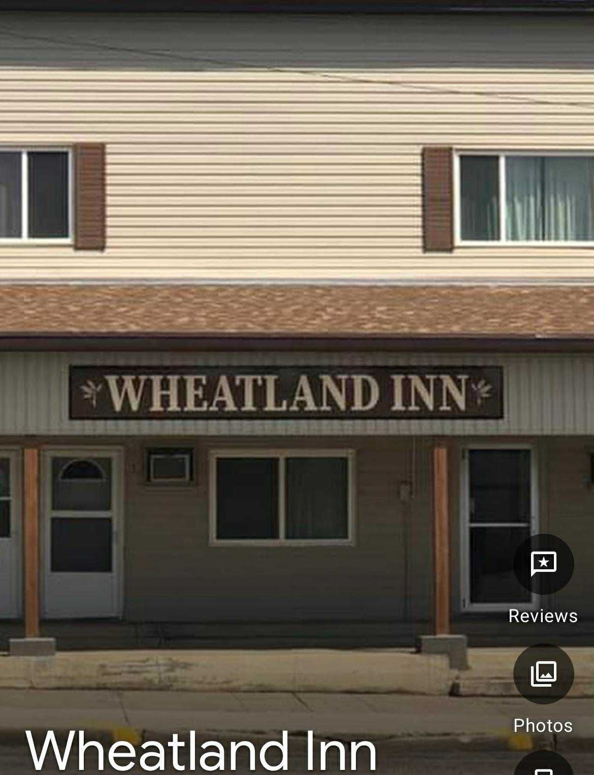 Wheatland Inn building exterior with cream siding, a brown sign, and two white entry doors.