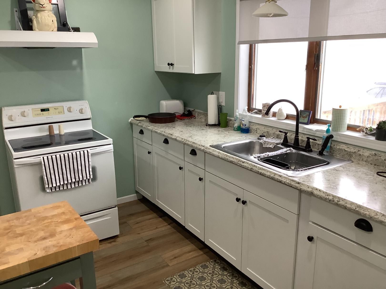 White kitchen with granite countertops, sink, and cabinets; stove on the left.