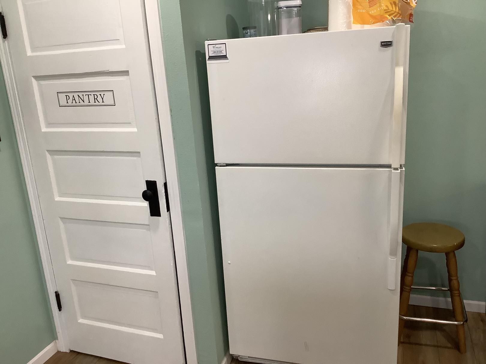 White refrigerator next to a white door labeled