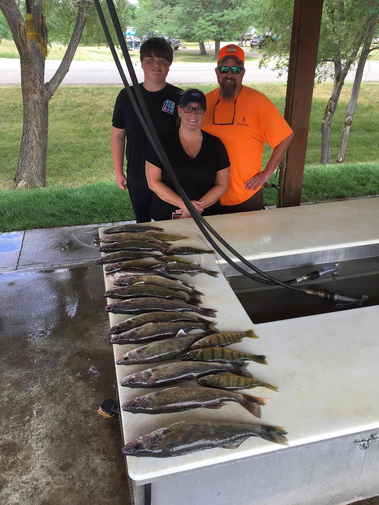 Family posing with a table of fish on a sunny day.