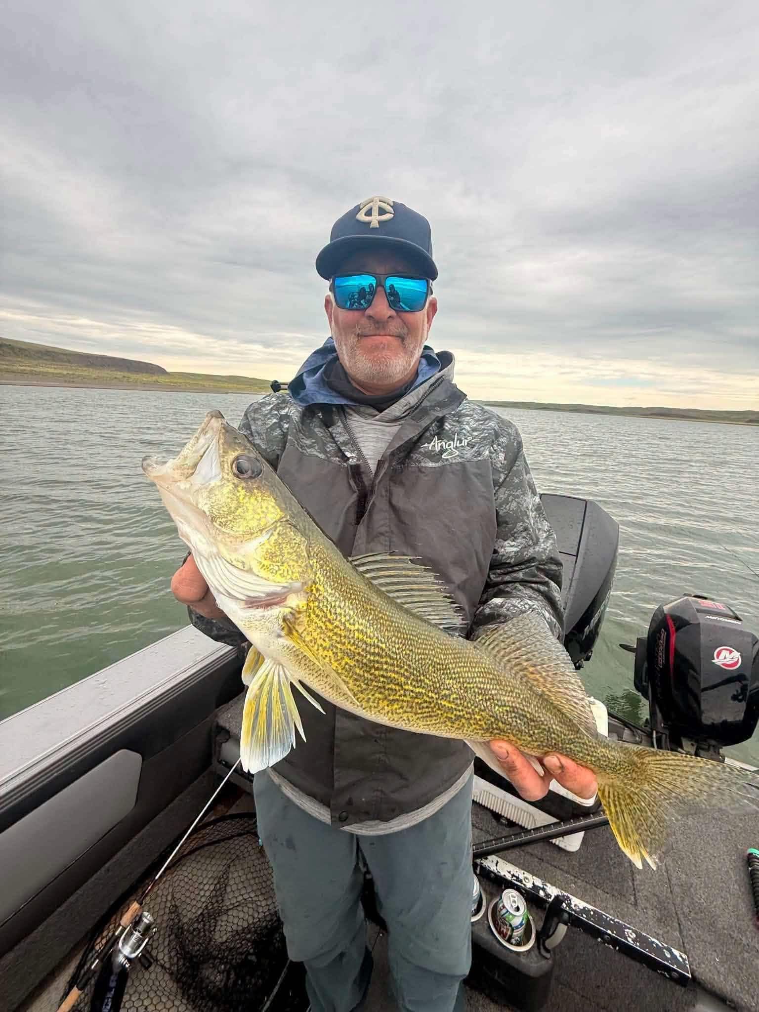 Angler on a boat holding a large South Dakota walleye on a cloudy lake