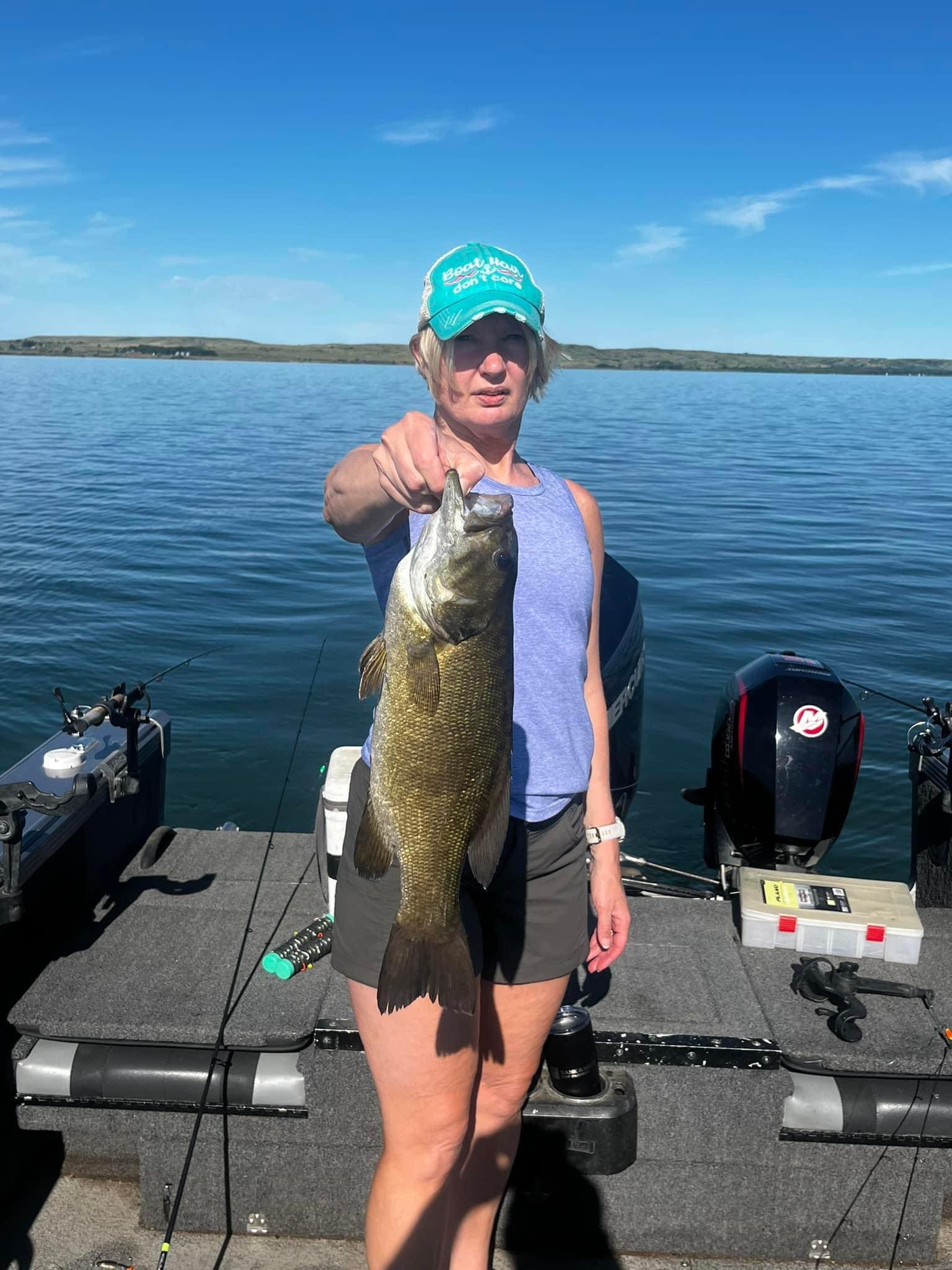 Woman holding a big fish on a boat in a lake Sharpe on a sunny day.