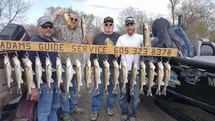 Four people holding up fish next to a boat with a sign that says 