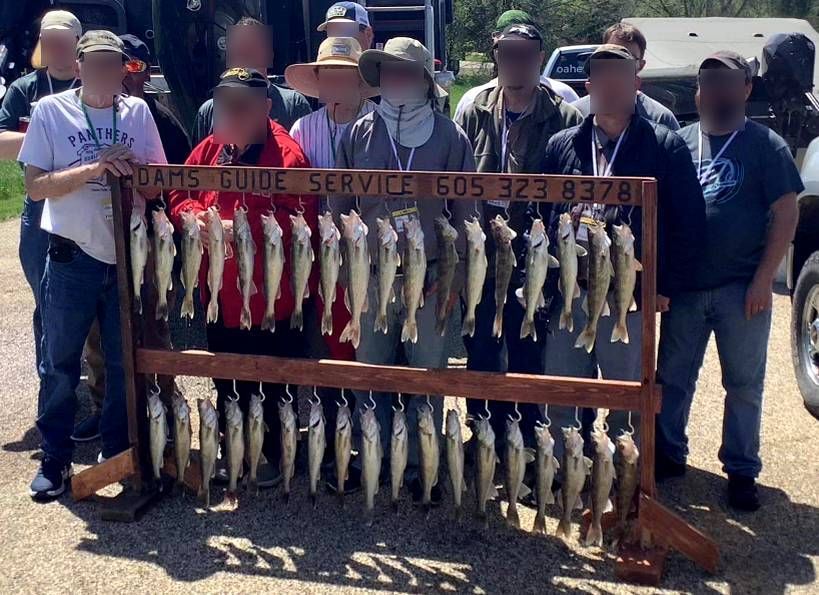 Group of people with a large rack displaying numerous fish, possibly a fishing excursion.