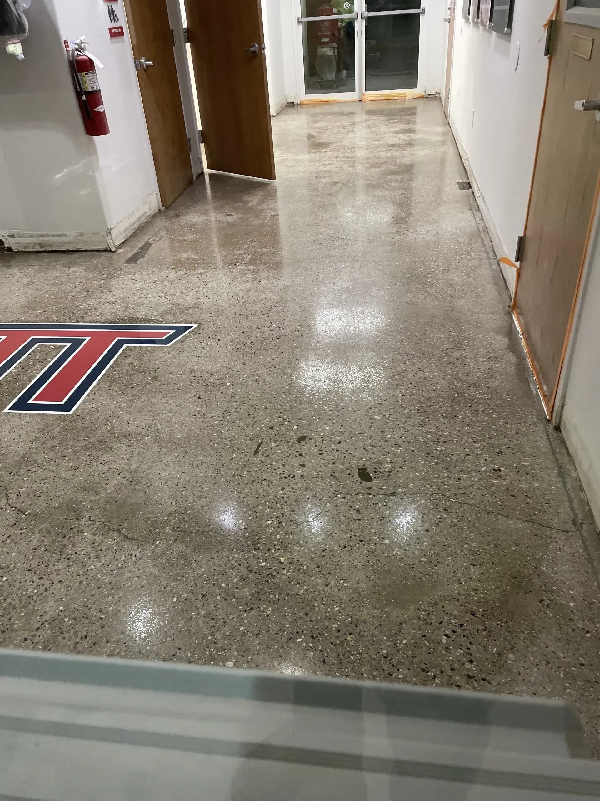 Polished concrete hallway with a Virginia Tech logo inlay. A red fire extinguisher is visible.