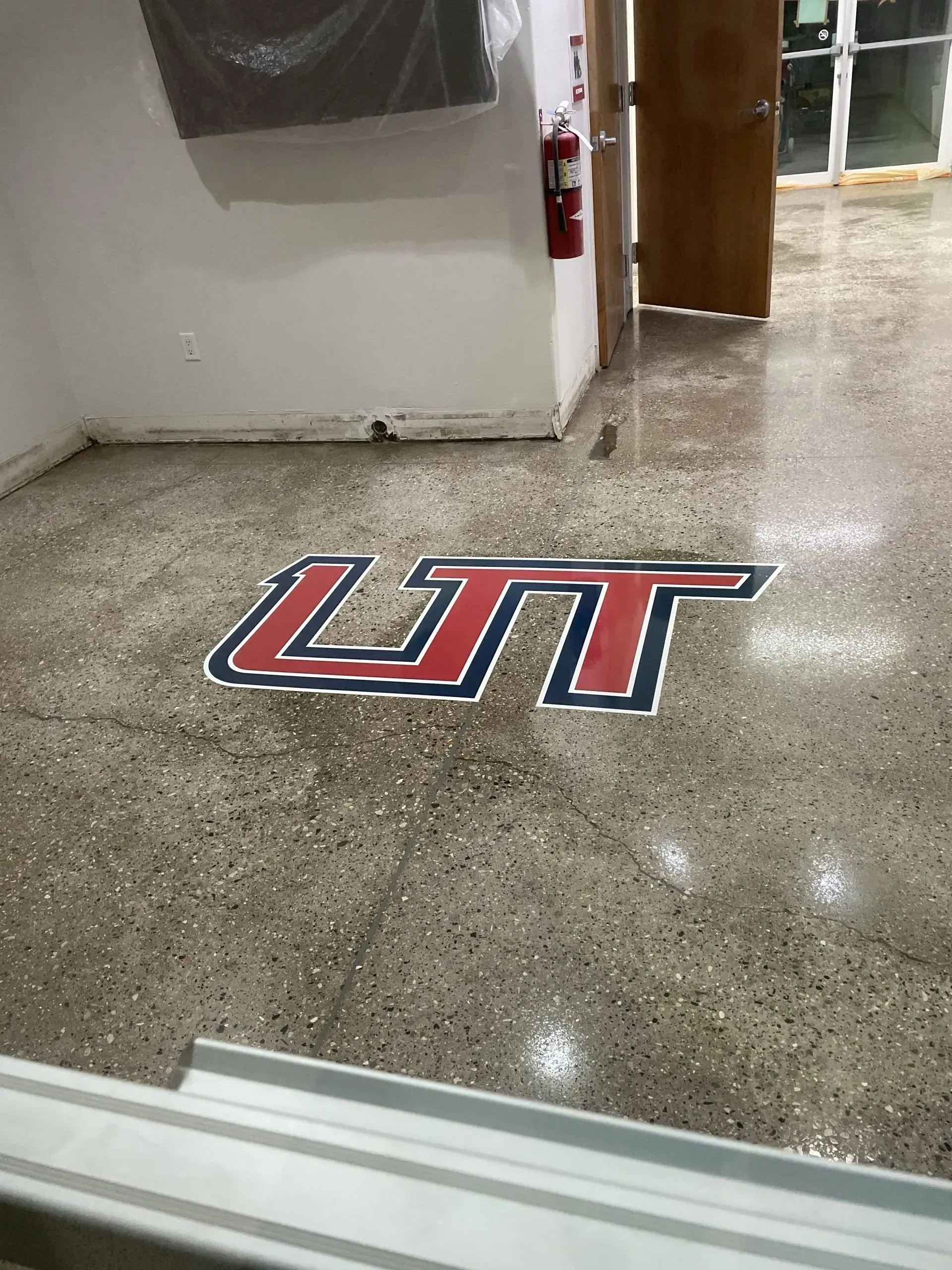 Floor with LTT logo in red, navy, and white. Inside building.