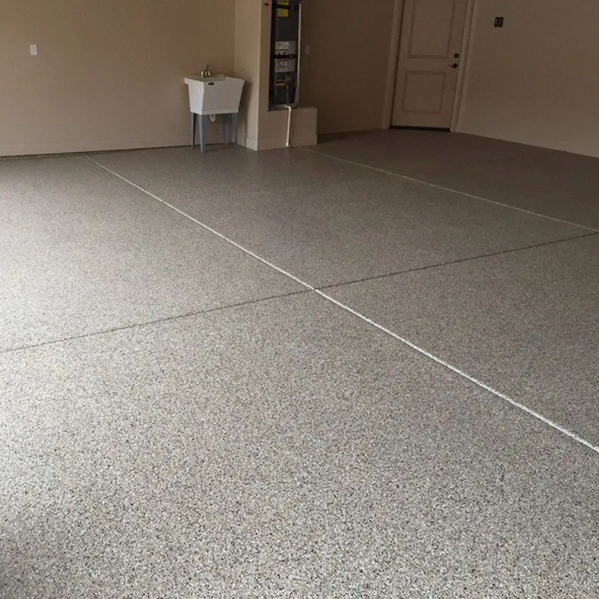 Garage with speckled gray flooring, a white sink, and a closed door.