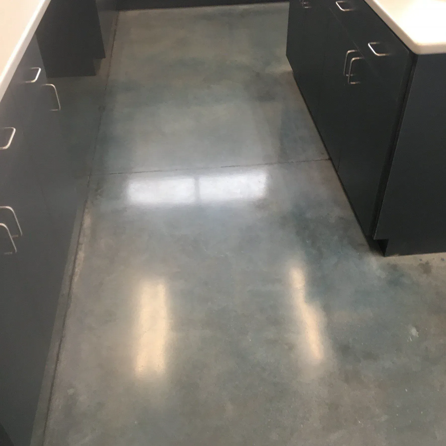 Gray concrete floor with dark cabinets and white countertops.