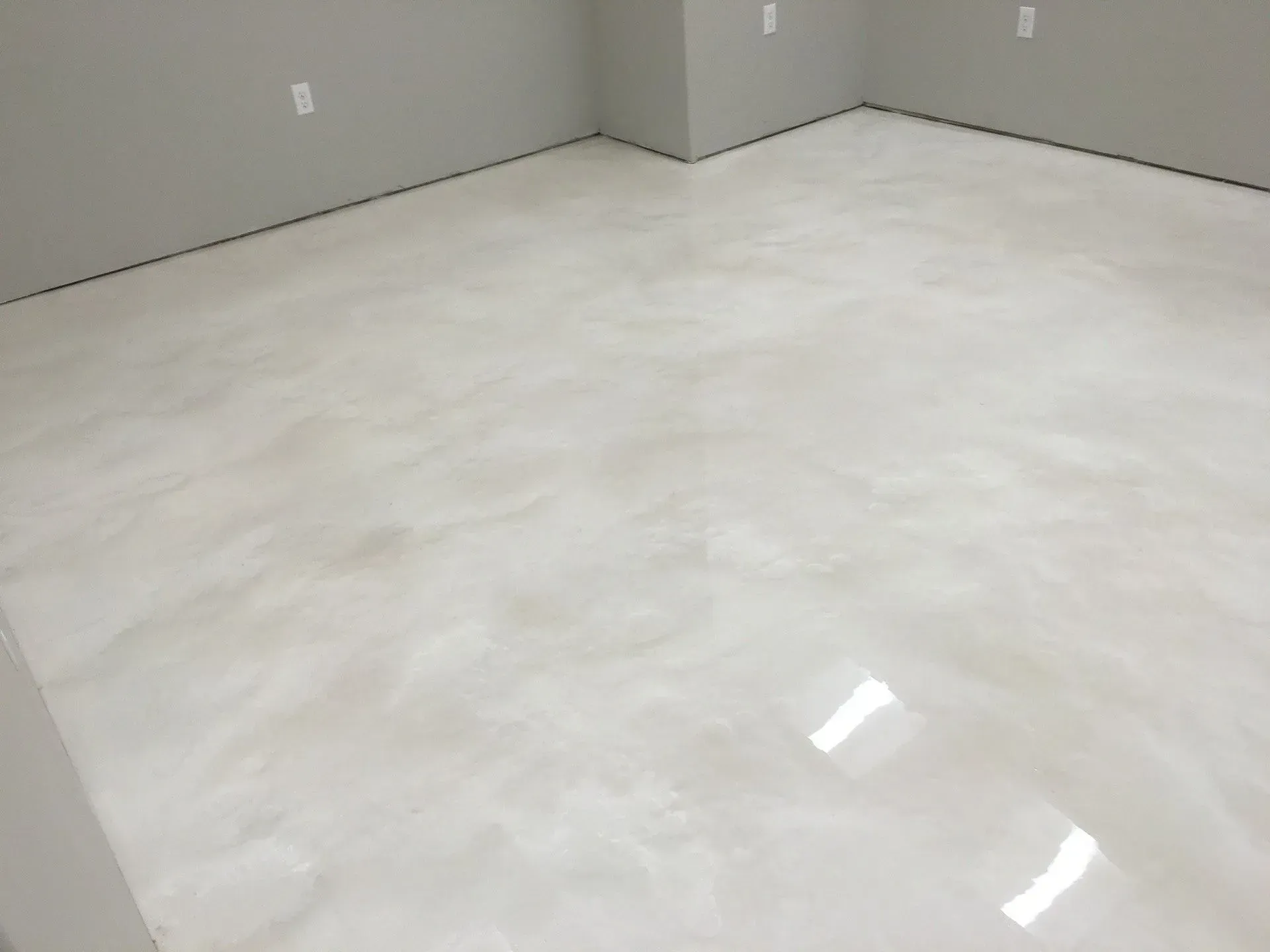 A room with a shiny, light-colored epoxy floor and light gray walls.