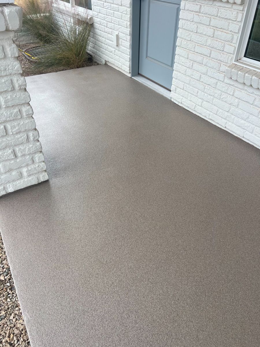 Brown-speckled concrete porch in front of a white brick house with a light blue door.