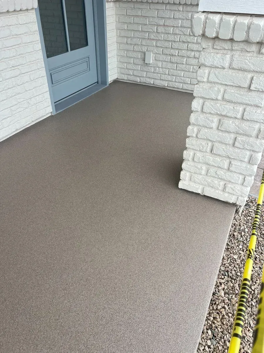 Front porch with a speckled brown concrete surface, painted brick columns, and a blue door.