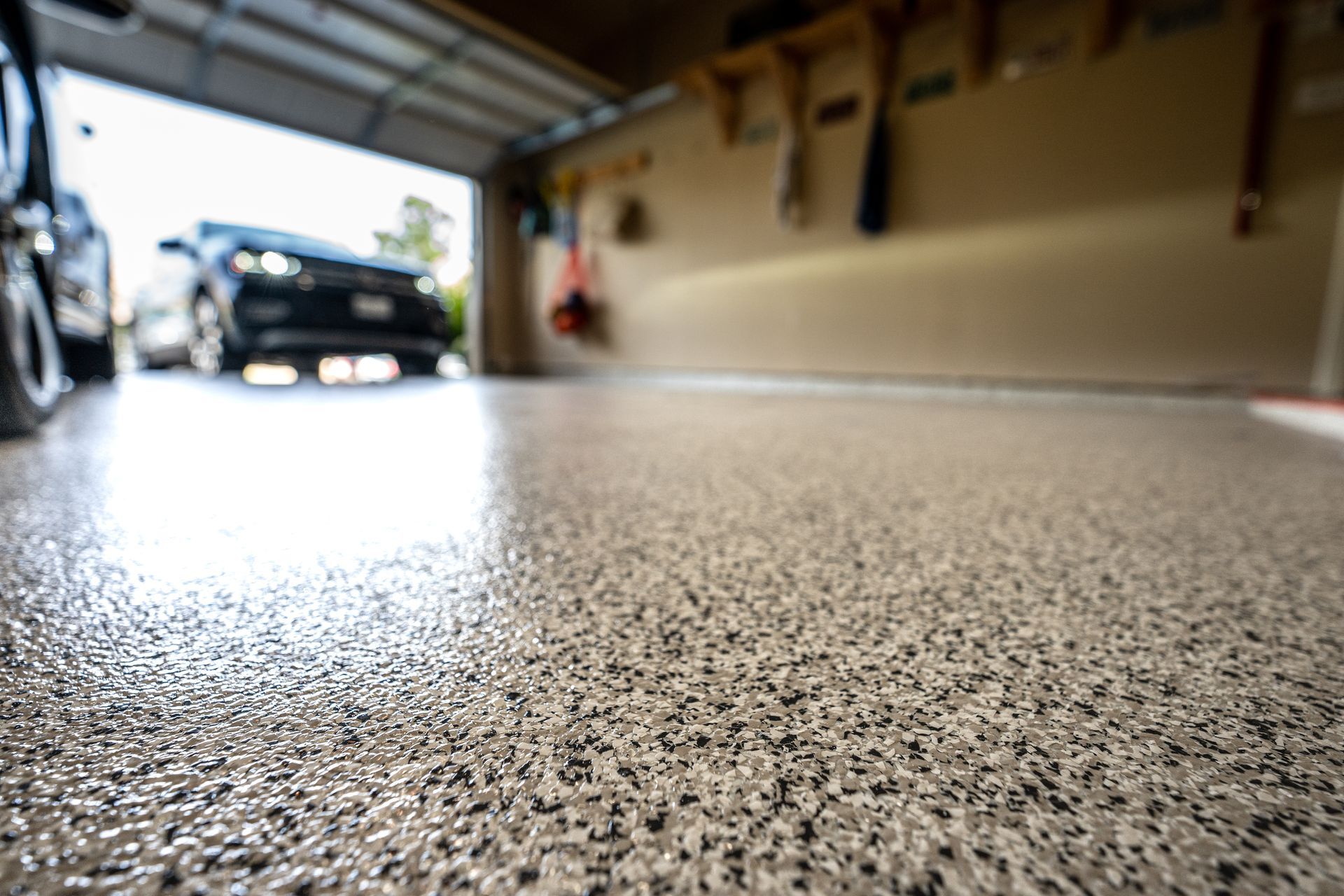 Shiny, speckled garage floor with a car parked inside and open garage door.