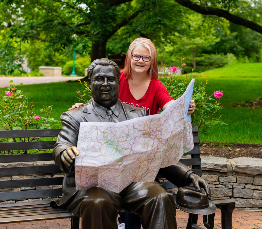 A woman smiling next to a beloved statue of Herman B Wells, former president of Indiana University
