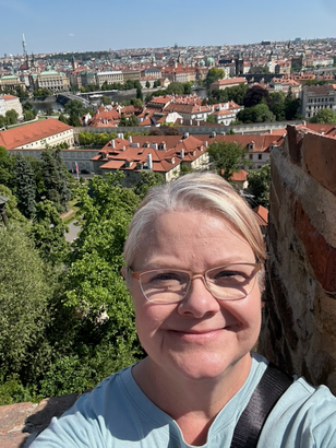 A picture of a woman with glasses against the background of a Prague neighborhood