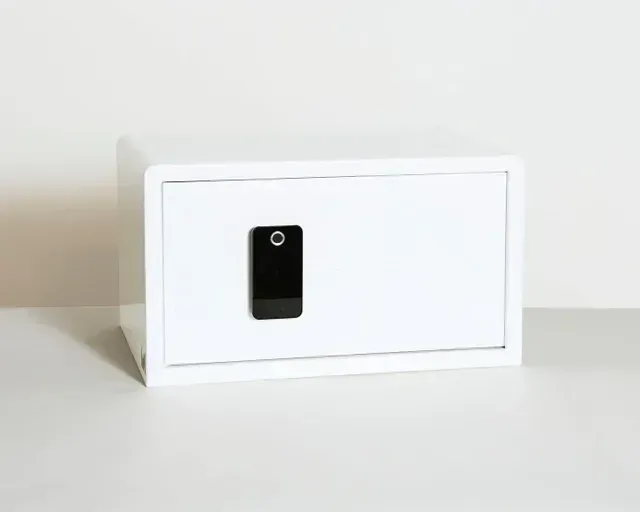 White safe with a black keypad on a white surface.